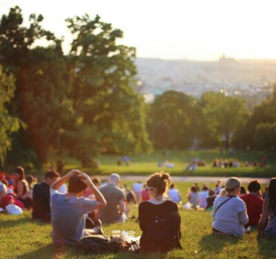 People sitting in groups together in a public garden in the sunshine.
