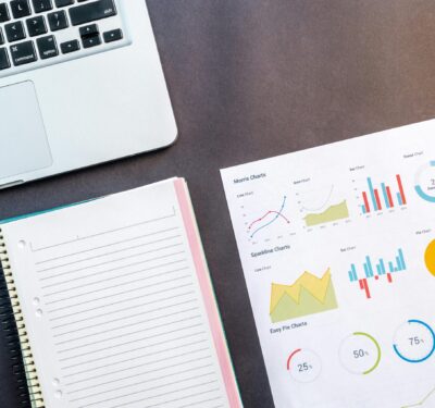 Laptop, notebook, and sustainability data charts on desk